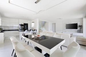 a white dining room with a black table and white chairs at Villa Eleni Di Mare in Kontokali