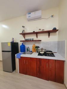 a kitchen with a sink and a stove and a refrigerator at Tayta Huasy in Montañita