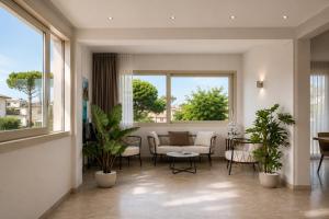 una sala de estar con dos ventanas y plantas en Hotel Amedea, en Cervia