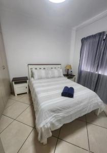 a bedroom with a white bed with two blue towels on it at Sea side cottage in Stilbaai