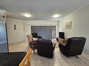 a living room with black leather chairs and a television at Sea side cottage in Stilbaai