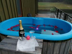 a blue tub with a bottle of wine and a glass at VIP forest dreams villa 2 in Leliūnai