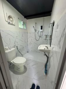 a white bathroom with a toilet and a sink at เหนือสะปัน in Ban Huai Ti