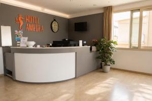 Un vestíbulo con un mostrador con un reloj en la pared. en Hotel Amedea, en Cervia