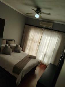 a bedroom with a bed and a ceiling fan at NAMOLEKA House- Bloemfontein in Bloemfontein +78 photos