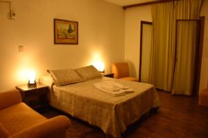 a hotel room with a bed and two chairs at SUIZO Hotel in Colonia Suiza