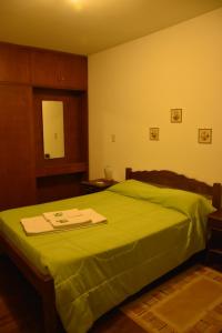 a bedroom with a bed with a green blanket at SUIZO Hotel in Colonia Suiza