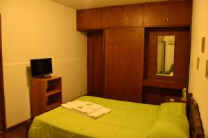 a small bedroom with a green bed and a tv at SUIZO Hotel in Colonia Suiza