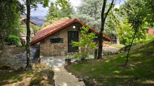 a small building with a red roof next to a river at Moose House EV Charging Pool Gated Community in Loivos