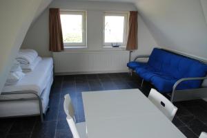 een kleine kamer met een blauwe bank en een tafel bij Gouden Plakje in Gaastmeer
