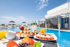 a table topped with plates of food next to a pool at Studio in a family hotel in Perivolos