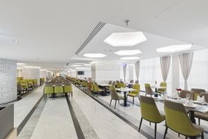 a dining room with tables and yellow chairs at Taj Park Hotel in Mecca