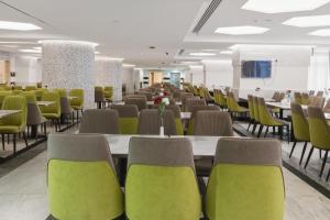 a dining room with tables and chairs with green chairs at Taj Park Hotel in Mecca