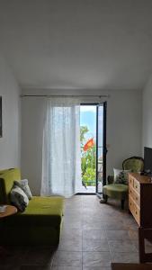 a living room with a green couch and a sliding glass door at Boutique Home Saltaragazza in Petrovac na Moru