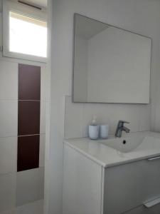 a white bathroom with a sink and a mirror at Garde barrières N 22 in Cholet