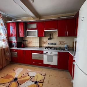 a kitchen with red cabinets and a white stove top oven at Two bedroom in Park Zone in Kamianets-Podilskyi +11 photos