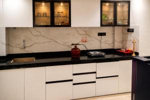 a kitchen with white cabinets and black counter tops at Vista Royal 2BHK With Private Pool in Igatpuri