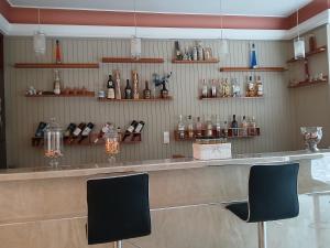 a bar with two chairs and bottles on the wall at Hermes in Agia Marina Aegina