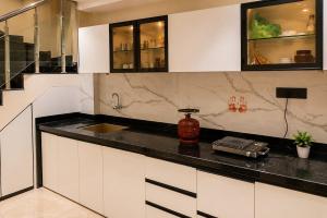 a kitchen with white cabinets and a black counter top at Vista Royal 2BHK With Private Pool in Igatpuri