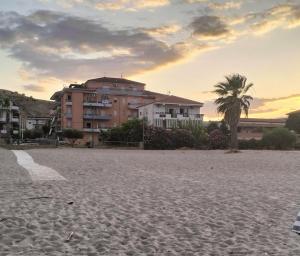 a building on a sandy beach with a palm tree at Sole di Vita in Marina di Strongoli