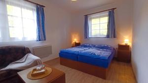 a bedroom with a blue bed and a couch at Penzion U kostela Mláka in Mláka +49 photos