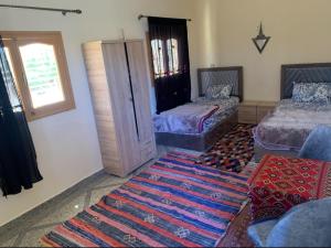a living room with two beds and a rug at Tinejdad Auberge in Tinejdad