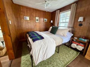 a bed in a room with wooden walls and a window at Highland House and Cottages in Carroll