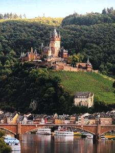 a castle on a hill with a bridge and boats at Stadtblick in Cochem