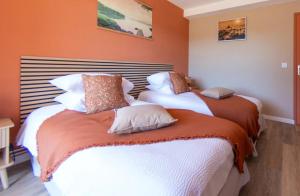 two beds in a room with orange walls at Maison du Pech in Carlux +40 photos
