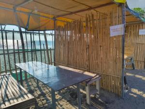 a picnic table under a tent next to the beach at Elyu Seaside in San Juan +1 photo