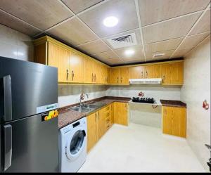 a kitchen with a refrigerator and a washing machine at Abdulla al Shaiba in Jazīrat al Ḩibāb