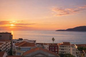 a sunset over a city with buildings and the ocean at Sea View Apartment Rafailovići in Rafailovici