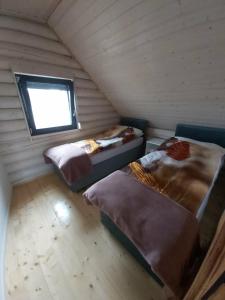 two beds in a room with a window at Domki letniskowe Malina 4 in Gawrony +6 photos