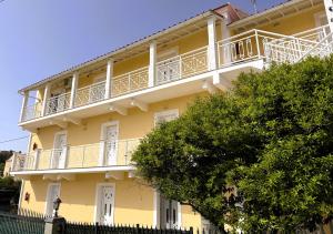 a yellow apartment building with a white balcony at Celestine Apartment, Arillas, Korfu in Arillas