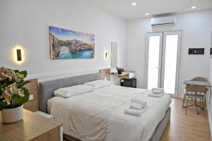 a white bedroom with a large bed and a table at Adriatic Breeze Rooms in Mola di Bari
