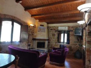 a living room with a fireplace and purple chairs at Villaggio dei Balocchi in Castelbuono