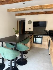 a kitchen with a black table and green chairs at Maison de l'olivier in Taradeau +14 photos