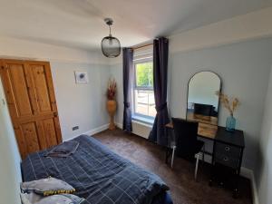 a bedroom with a bed and a desk and a mirror at Carisbrooke Mill Cottage in Newport