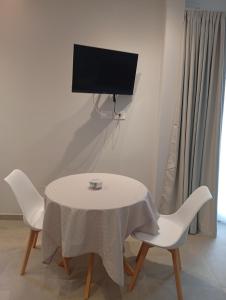 a white table with two chairs and a tv on a wall at La Porta Rossa House in Castelbuono
