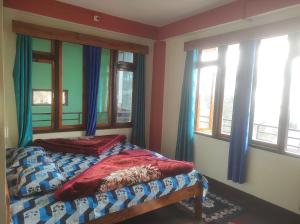 a bedroom with a bed and two windows at Laxmi Homestay in Kalimpong