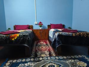 a room with two beds and a rug on the floor at Laxmi Homestay in Kalimpong