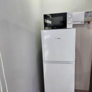 a white refrigerator with a microwave on top of it at Cozy & Modern Apartment -Self Catering in Pretoria