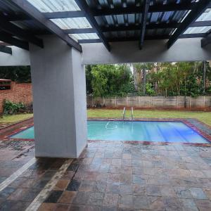 a swimming pool in a yard with a roof at Cozy & Modern Apartment -Self Catering in Pretoria