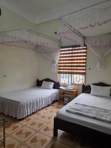 a bedroom with two beds and a window at Nhà nghỉ Homestay Minh Hạnh in Nà Phia +22 photos