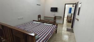 a bedroom with a bed and a tv on a wall at Santha Residency in Ambātturai