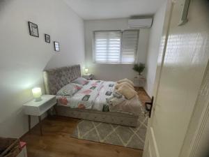 a small bedroom with a bed and a window at Fenix Apartman II in Zaječar