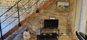 a living room with a tv and a stone wall at Charmante et Chaleureuse petite maison in Châteauneuf-du-Pape