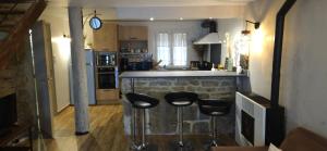 a kitchen with a bar with three stools in it at Charmante et Chaleureuse petite maison in Châteauneuf-du-Pape