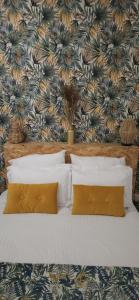 a bed with two pillows and a floral wallpaper at Charmante et Chaleureuse petite maison in Châteauneuf-du-Pape