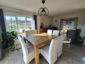 a dining room with a wooden table and white chairs at La clé des champs chambre d'hôtes in Theux